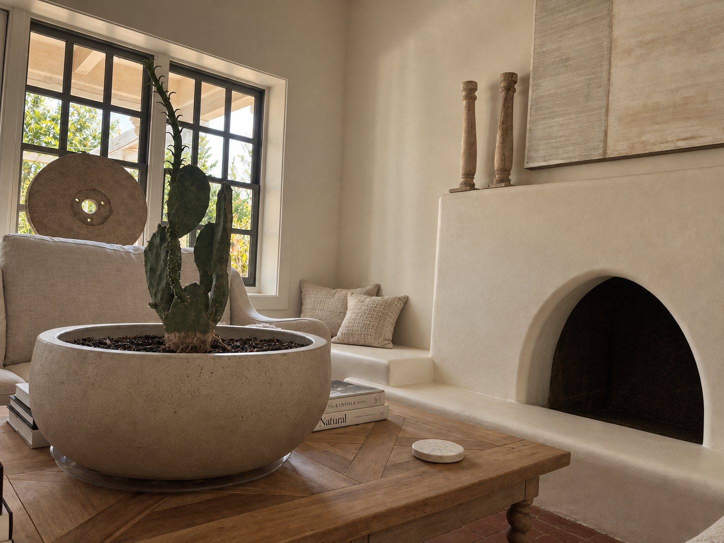 The Adobe interior with a sculptural fireplace, cactus planter and wood coffee table