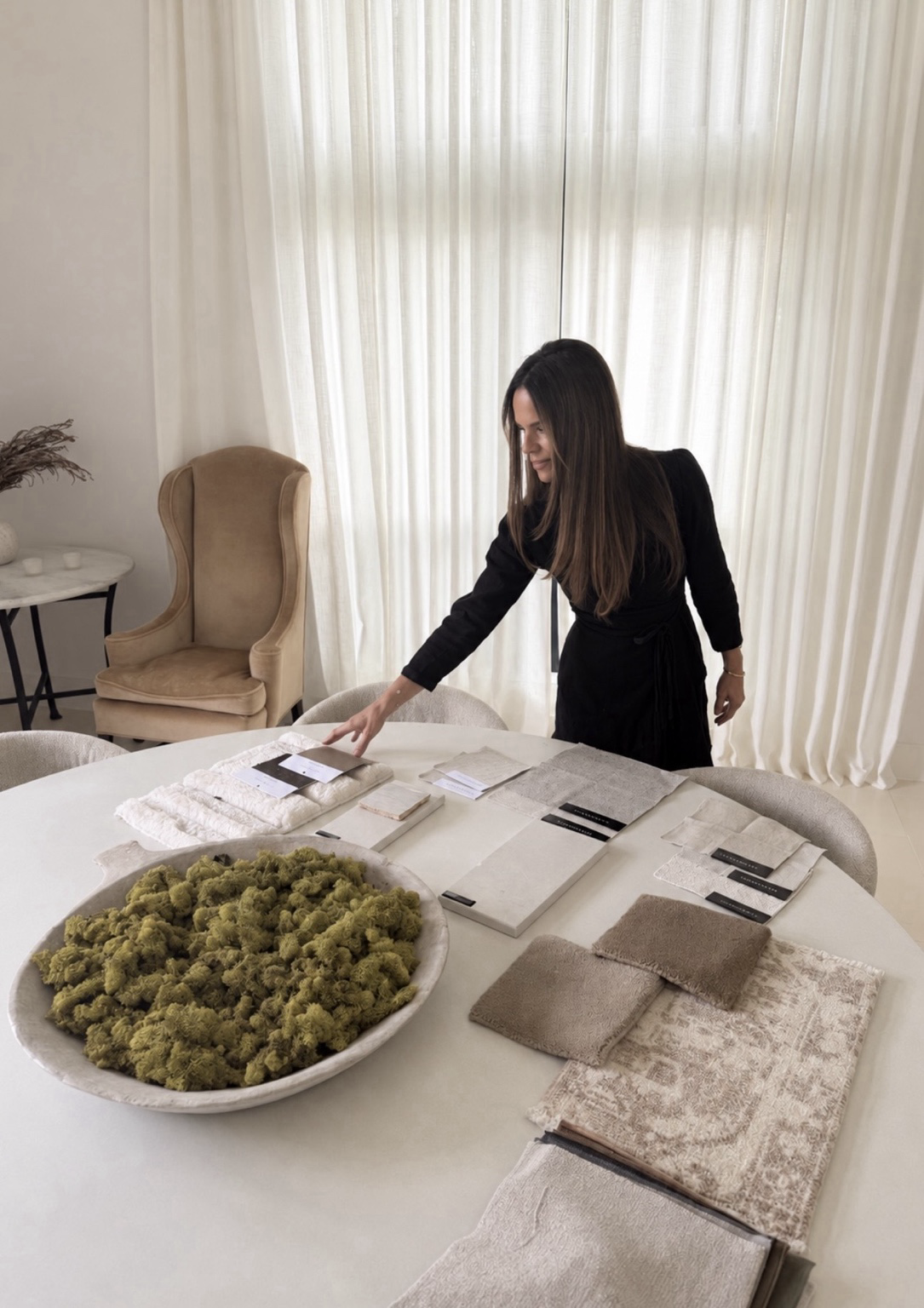 Lorri Brunacini Jones working with material samples, stone tiles, fabric swatches and preserved moss on a round studio table