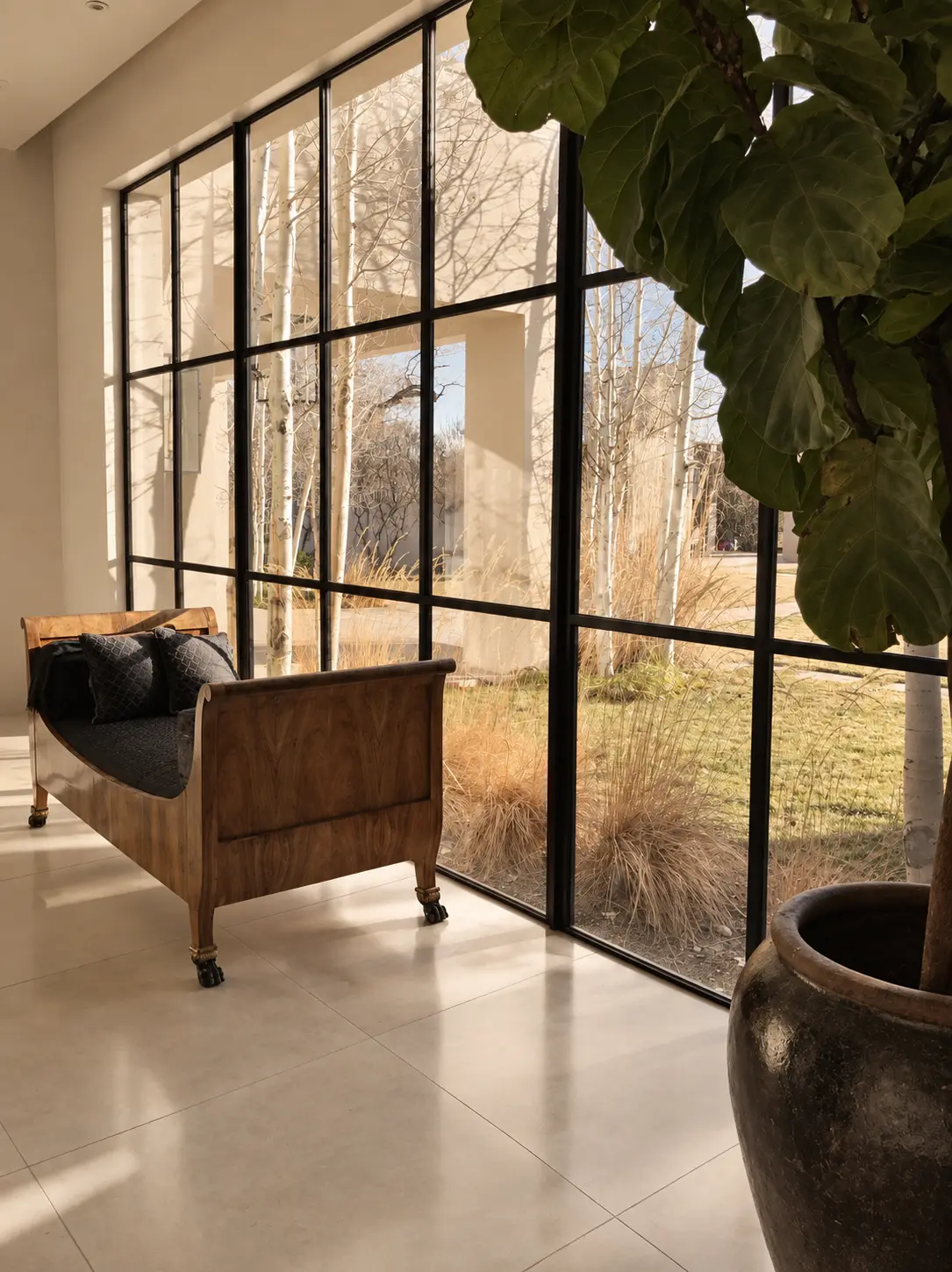 Antique wood settee beside floor-to-ceiling steel glazing
